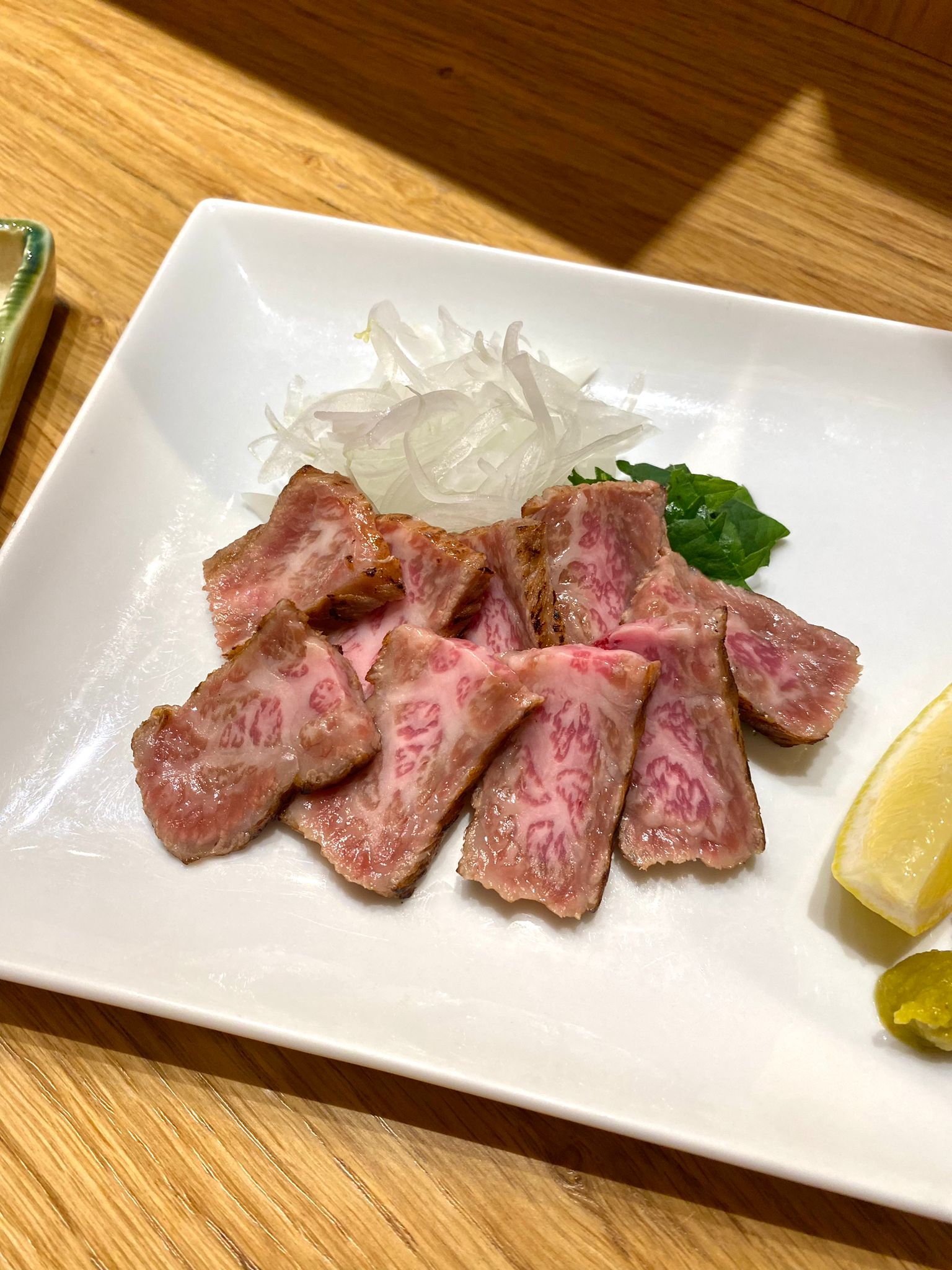 WAGYU TATAKI: Manzo giapponese scottato, servito con ponzu e rapa grattugiata con peperoncino, cipollotti.